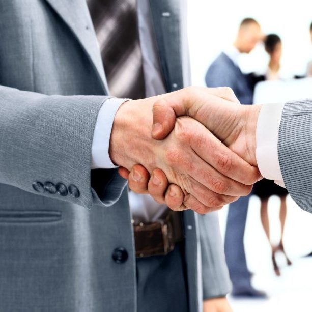businessmen-shaking-hands-with-team-behind
